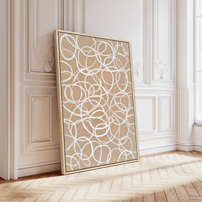 a large, abstract painting with a circular pattern on a white background, displayed on a wooden floor against a white wall.
