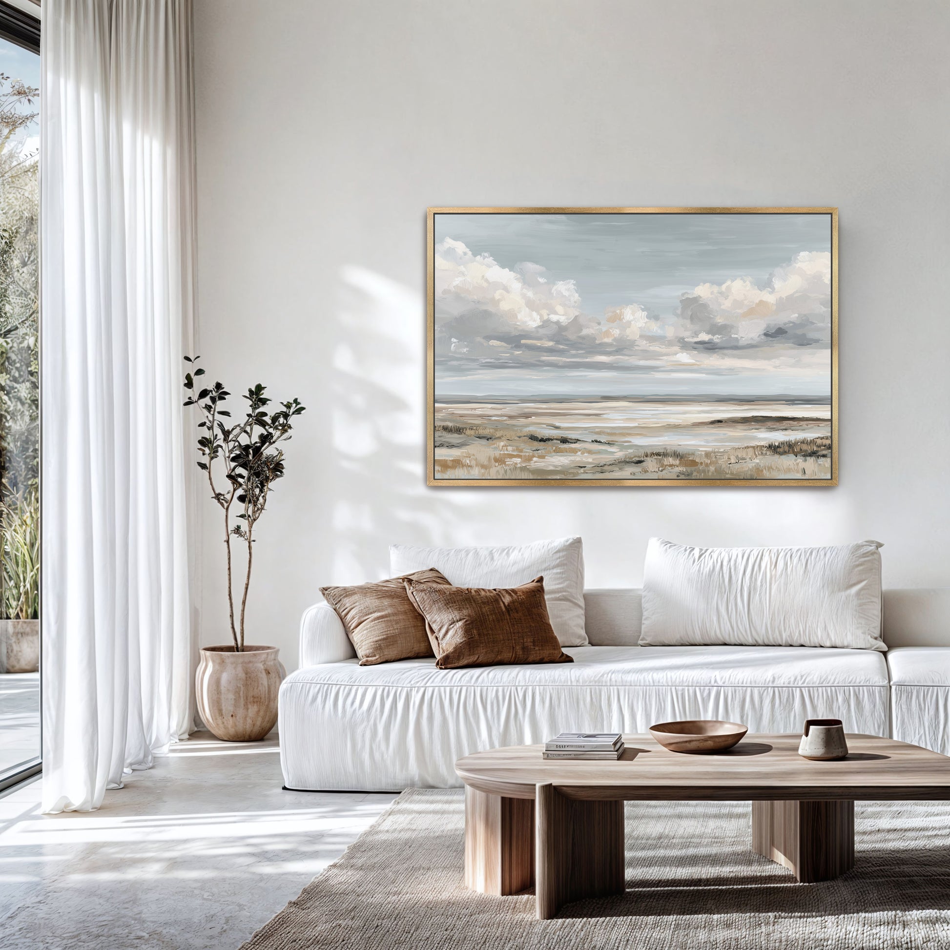 a serene living room with a large window, white sofa, and a wooden coffee table. A framed landscape painting hangs on the wall above the sofa, adding an artistic touch to the space.