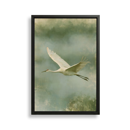 A white crane with outstretched wings is captured in flight against a backdrop of green and gray hues.