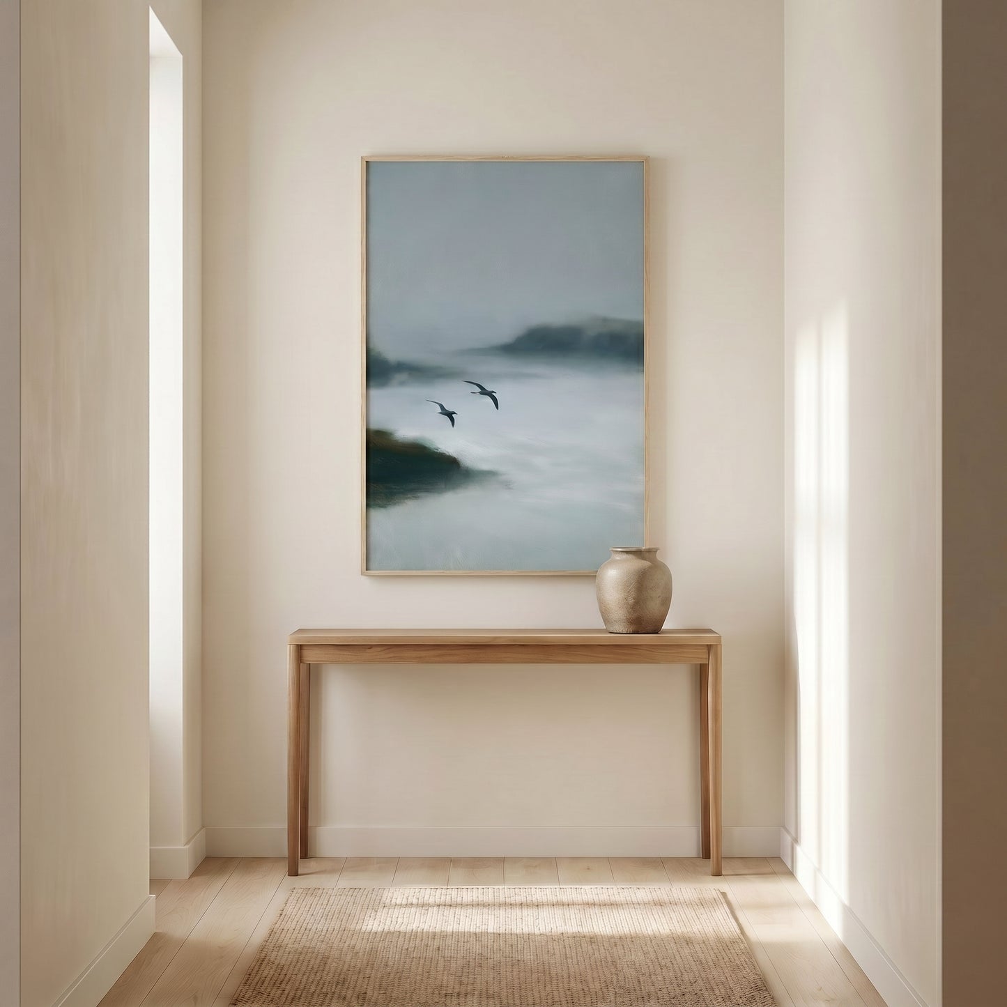 a serene indoor setting with a wooden console table and a framed painting of a misty landscape hanging on the wall.