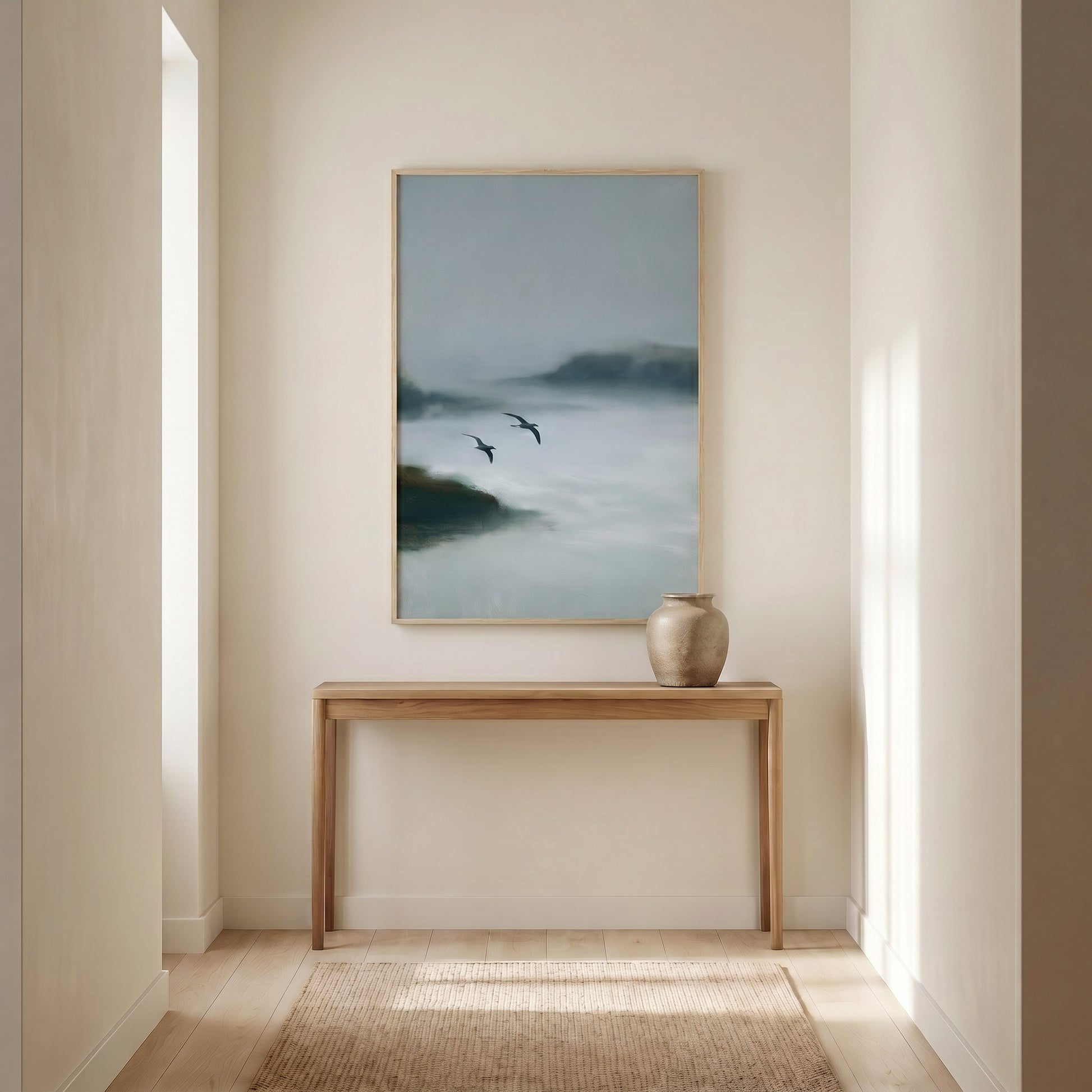 a serene indoor setting with a wooden console table and a framed painting of a misty landscape hanging on the wall.