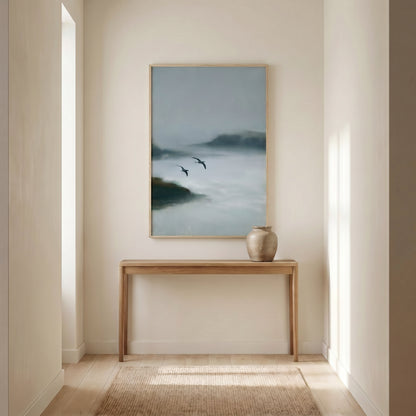 a serene indoor setting with a wooden console table and a framed painting of a misty landscape hanging on the wall.