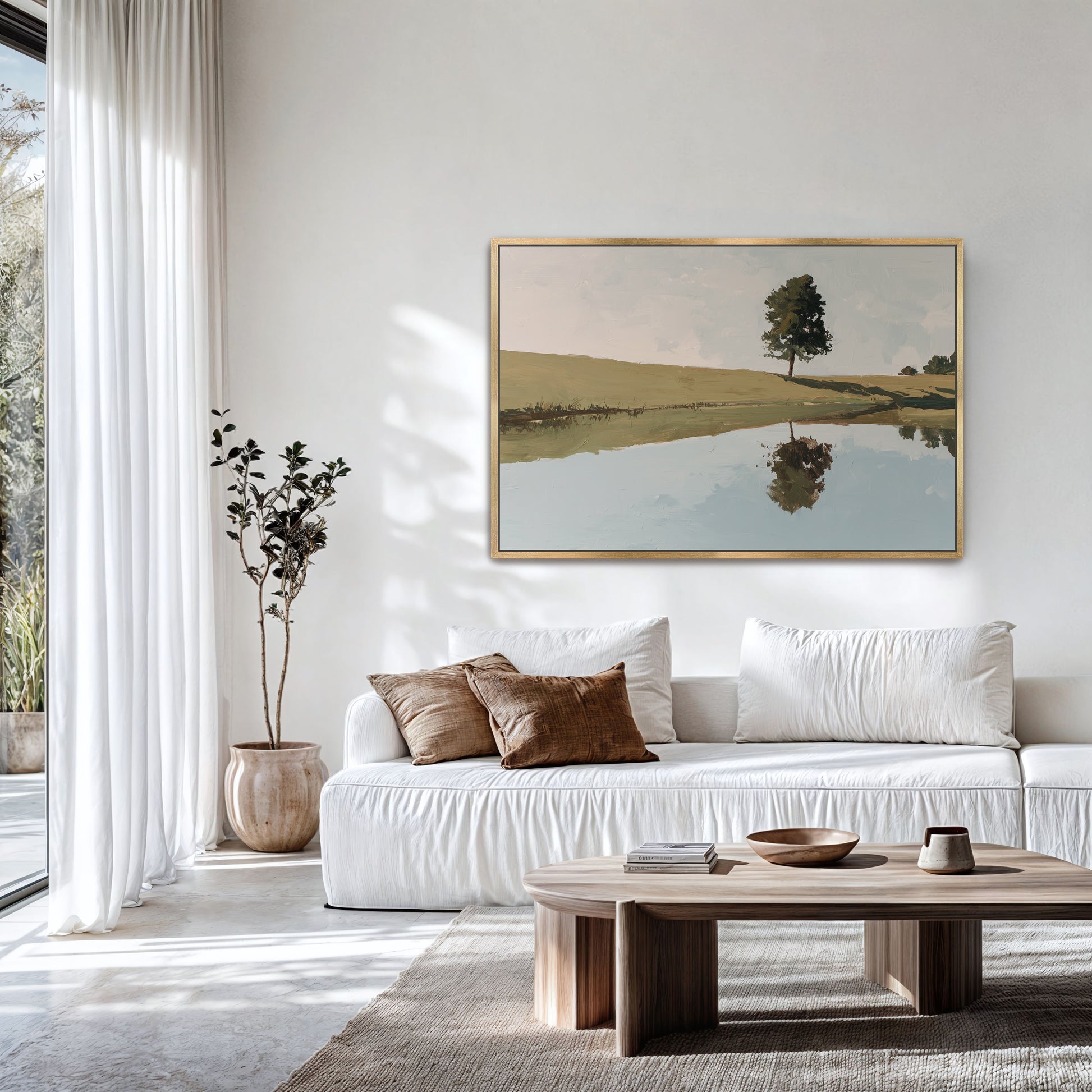 a serene living room with a white sofa, a wooden coffee table, and a large painting of a tree and a lake hanging on the wall.