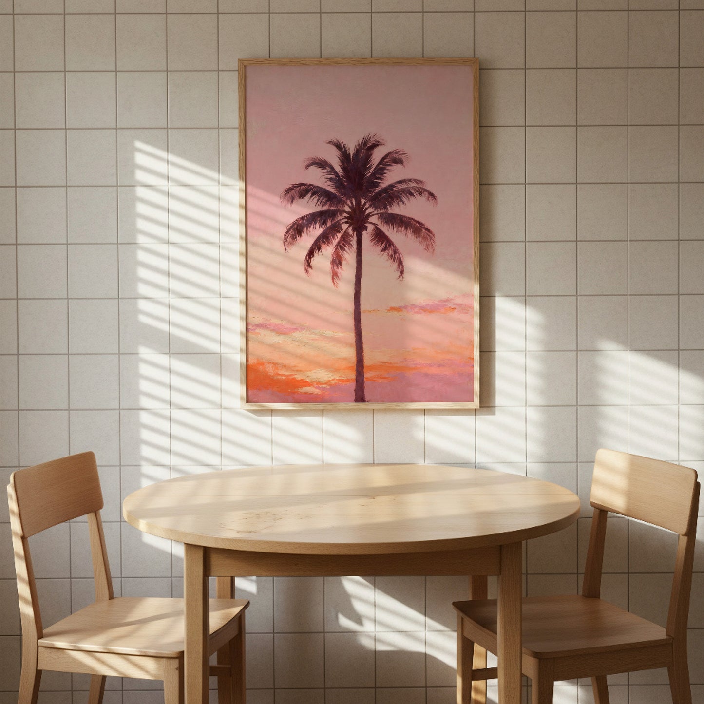 a wooden table with two chairs, set against a wall with a framed picture of a palm tree hanging above it.