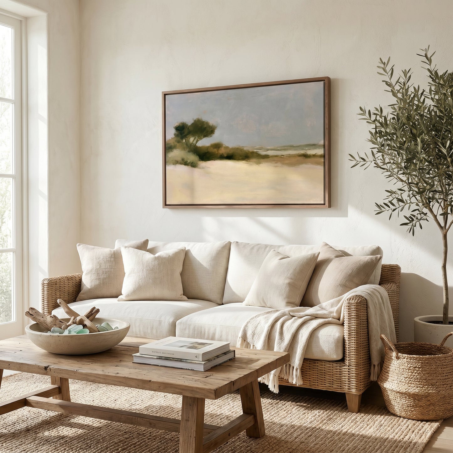 a cozy living room with a large painting of a landscape hanging on the wall above a beige sofa. The sofa is adorned with throw pillows and a blanket, creating a comfortable and inviting atmosphere. A wooden coffee table sits in front of the sofa, and a potted plant adds a touch of greenery to the space. The room is well-lit, with natural light streaming in from a window, and the overall decor has a warm and inviting feel.