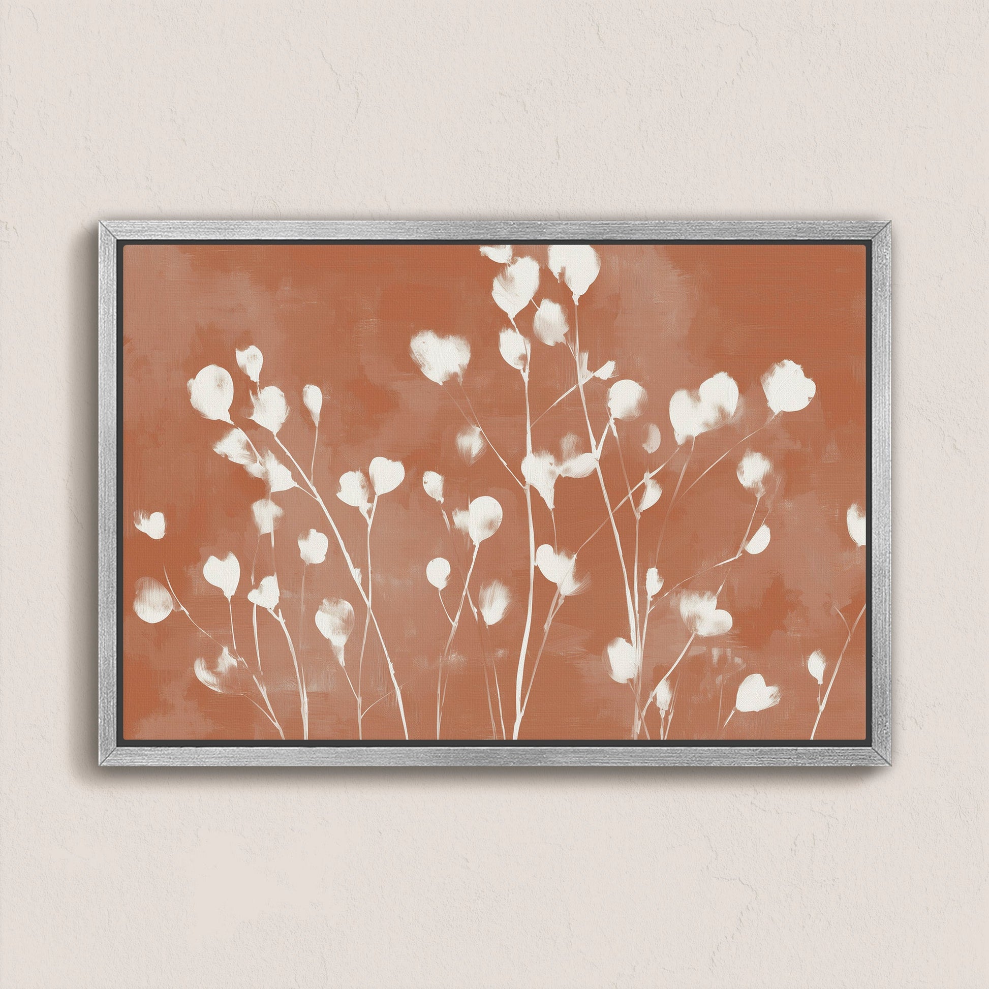 Ember canvas print with white floral petals on terracotta background in a minimalist silver frame