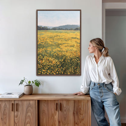 A woman stands in a room, leaning against a wooden cabinet, with a framed painting of a field of yellow flowers hanging on the wall above her.