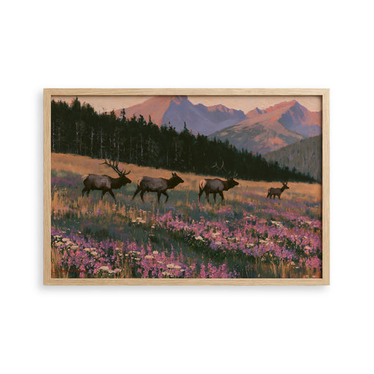A framed painting depicting a group of elk in a field with mountains in the background.