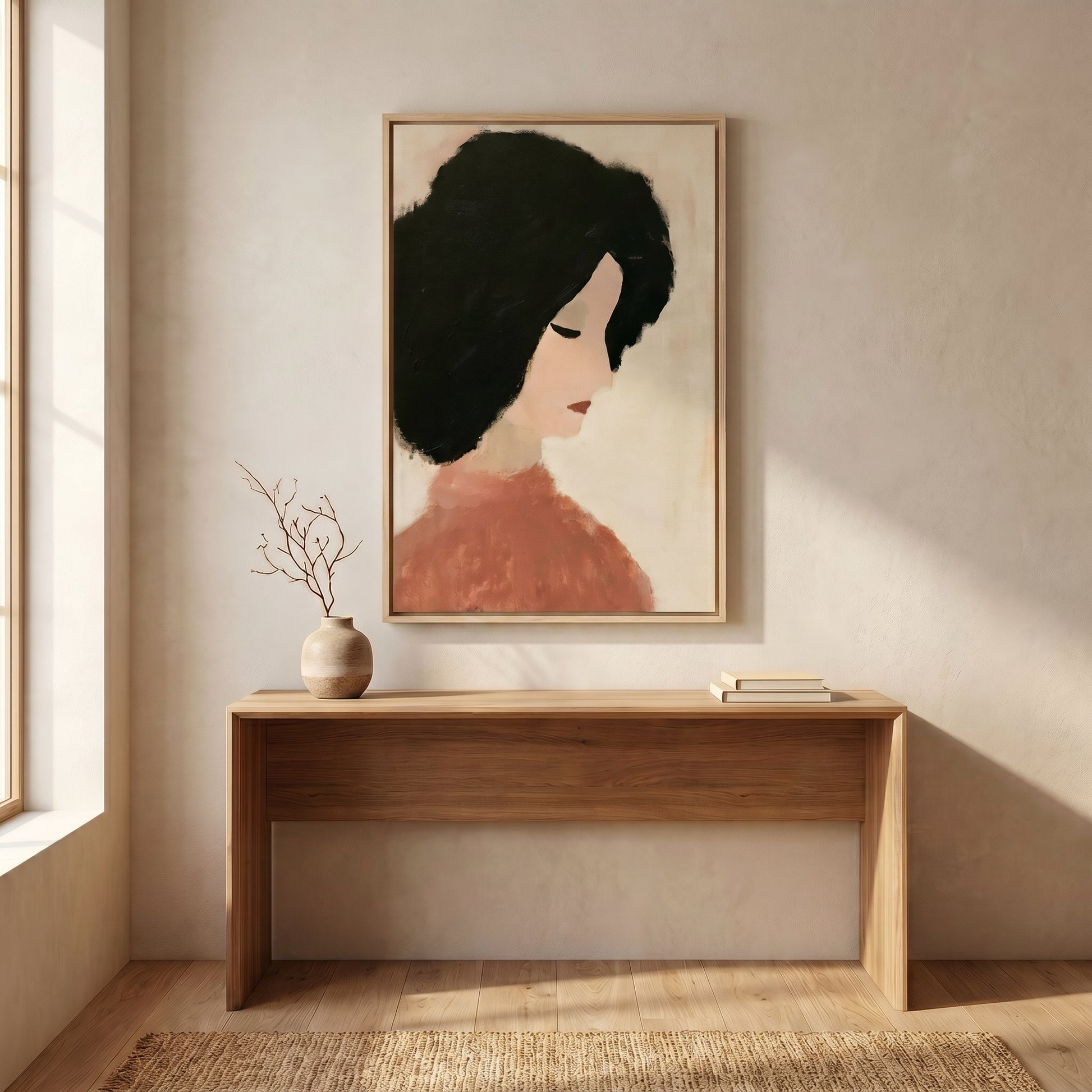 a wooden console table with a vase of branches and a stack of books on it, set against a light-colored wall with a framed portrait of a woman hanging above it.