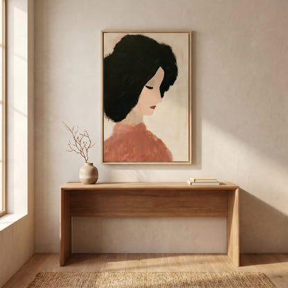 a wooden console table with a vase of branches and a stack of books on it, set against a light-colored wall with a framed portrait of a woman hanging above it.