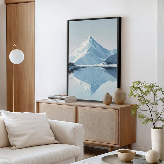 a living room with a large painting of a mountain landscape hanging on the wall, a white sofa, a wooden cabinet, and a potted plant.