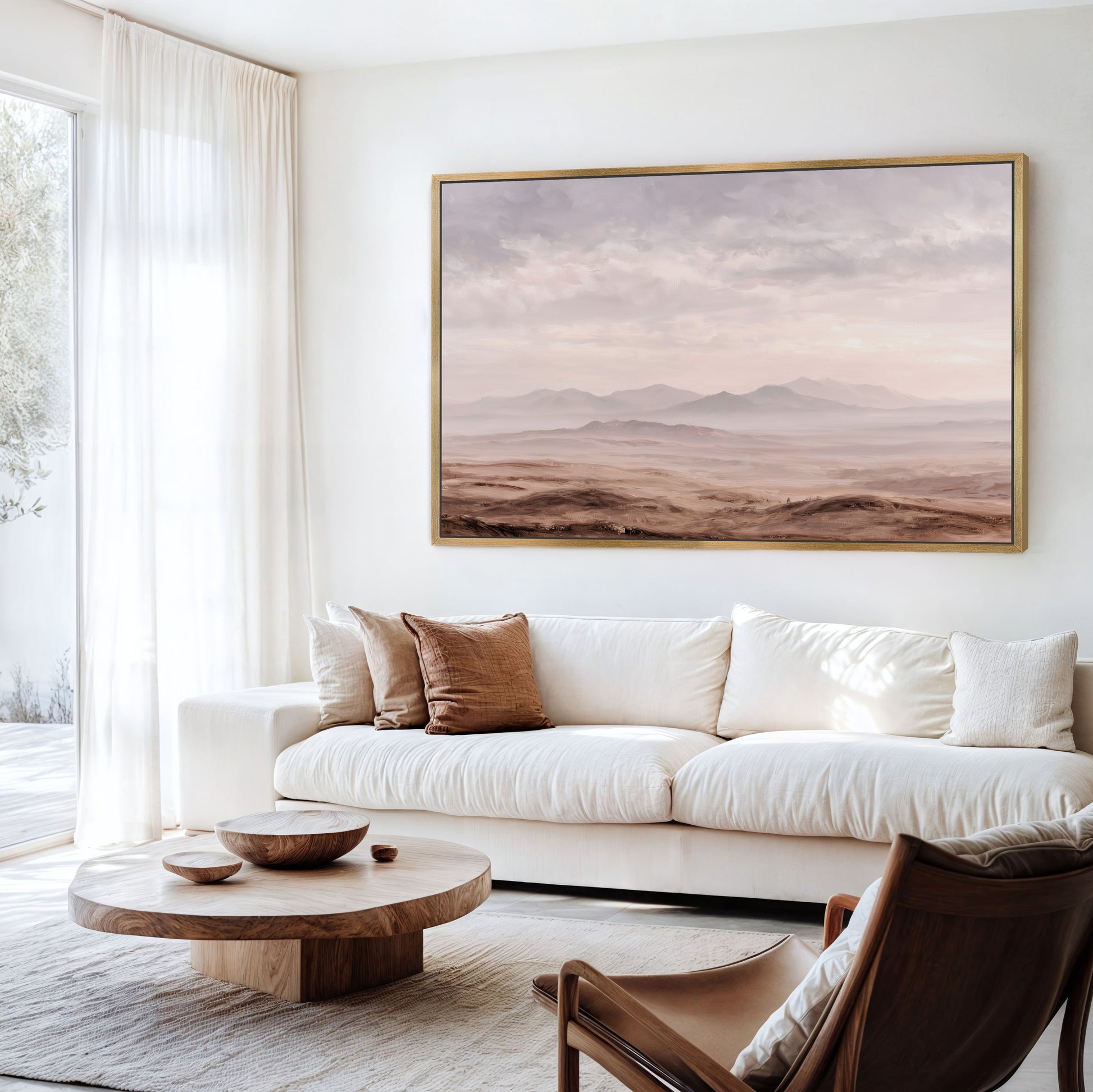 a serene living room with a large landscape painting hanging on the wall above a white sofa and a wooden coffee table.