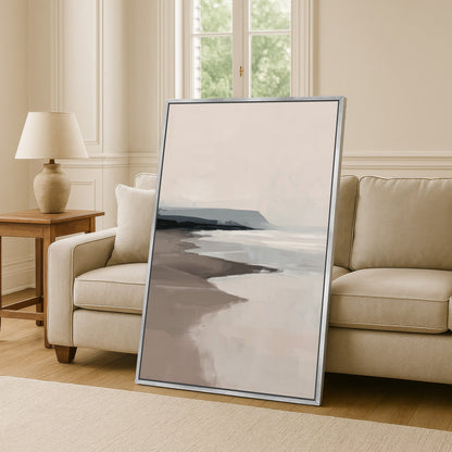 Minimalist coastal seascape in soft beige and gray tones Mel Canvas Print leaned against beige sofa in modern living room
