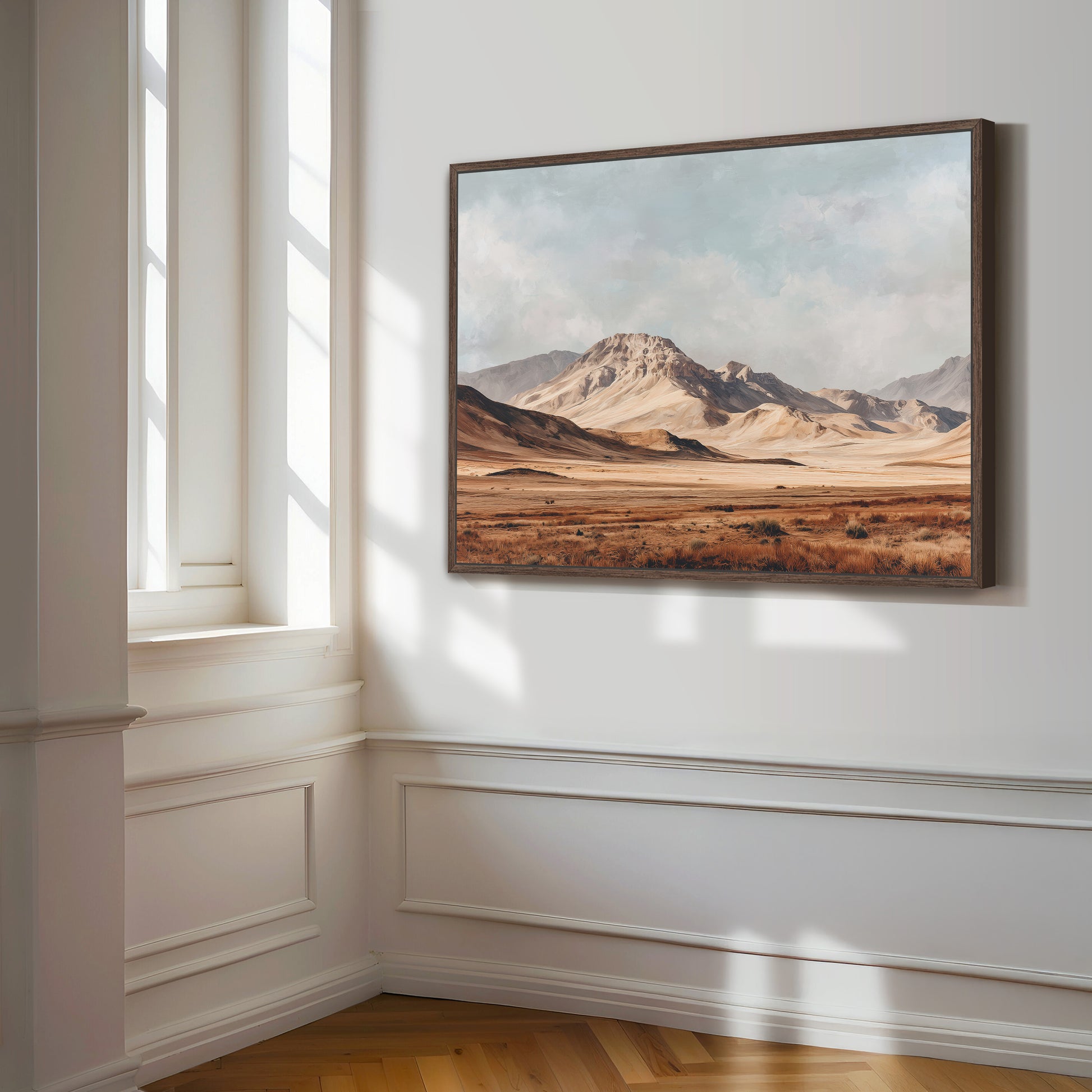a large landscape painting hanging on a white wall, depicting a desert scene with mountains in the background.