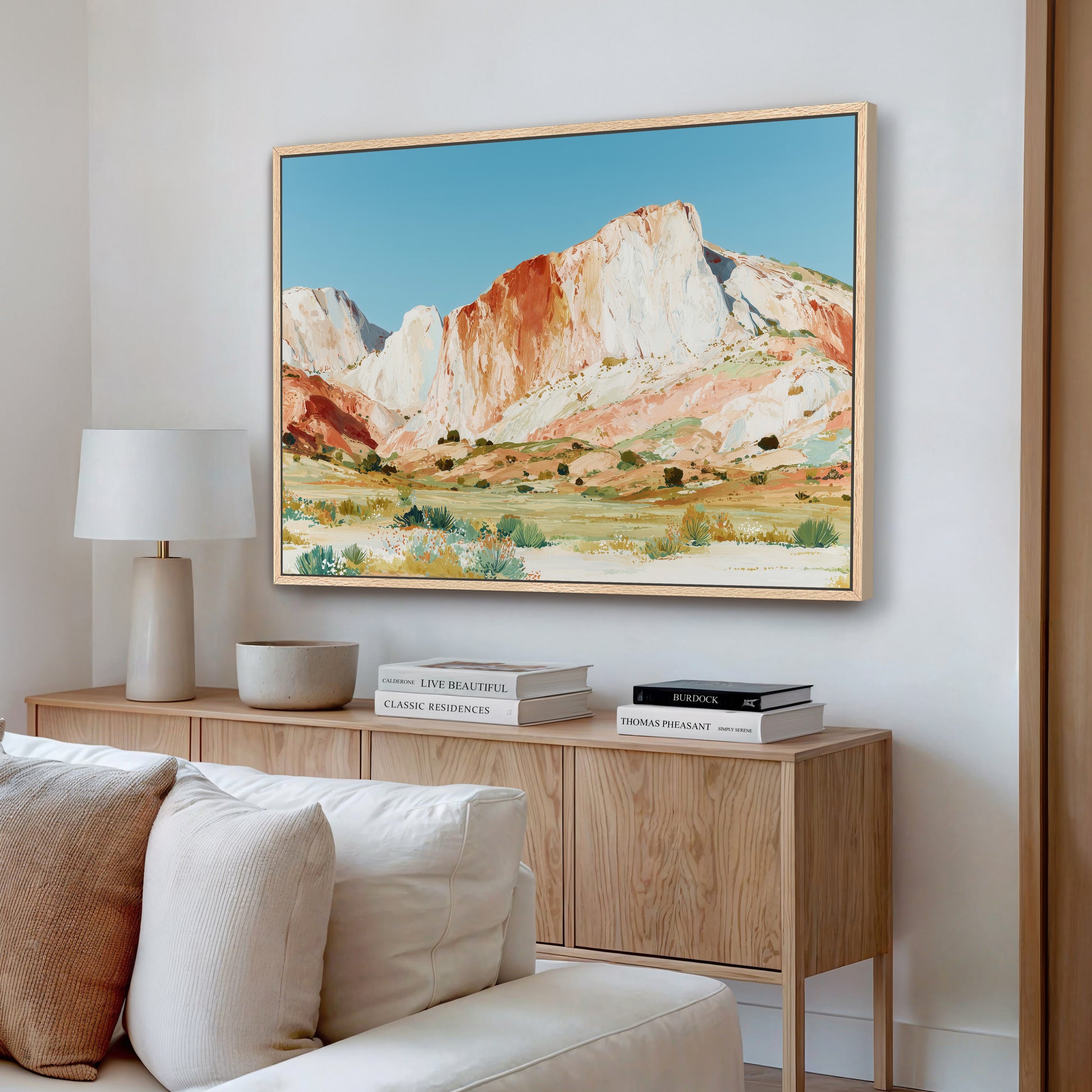 a large framed painting of a mountainous landscape hanging on a wall in a living room.