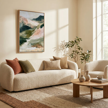 a cozy living room with a large abstract painting on the wall, a plush white sofa with colorful throw pillows, a wooden coffee table, and a potted plant.