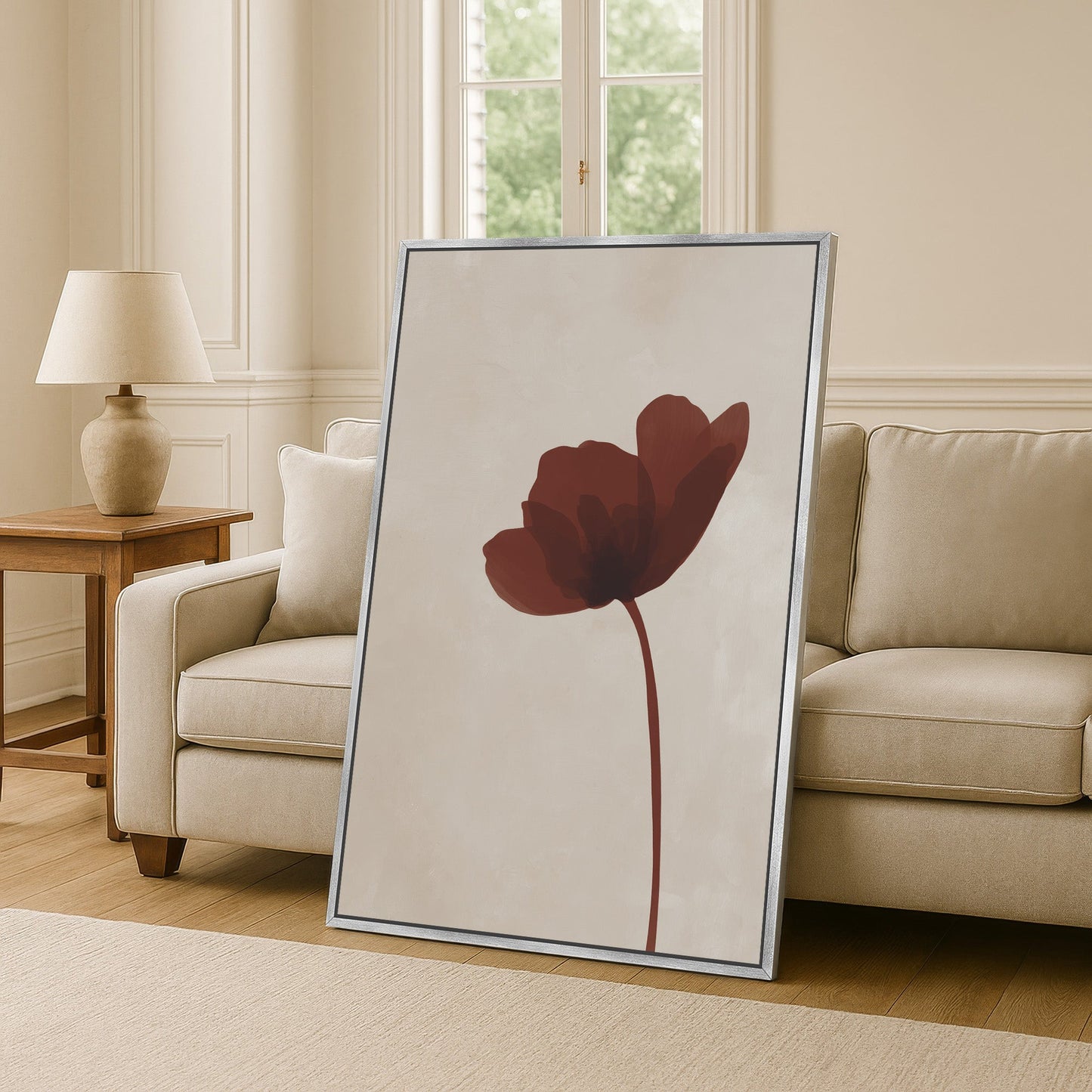 Minimalist Stem Canvas Print featuring a single burgundy flower on a neutral background, framed and leaning against a beige sofa in a modern living room.