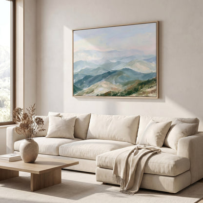 a serene living room with a large painting of a mountainous landscape hanging on the wall above a beige sofa. The sofa is adorned with a vase of dried flowers and a throw blanket, adding a touch of warmth and coziness to the space. The room is illuminated by natural light coming through a window, creating a bright and inviting atmosphere.