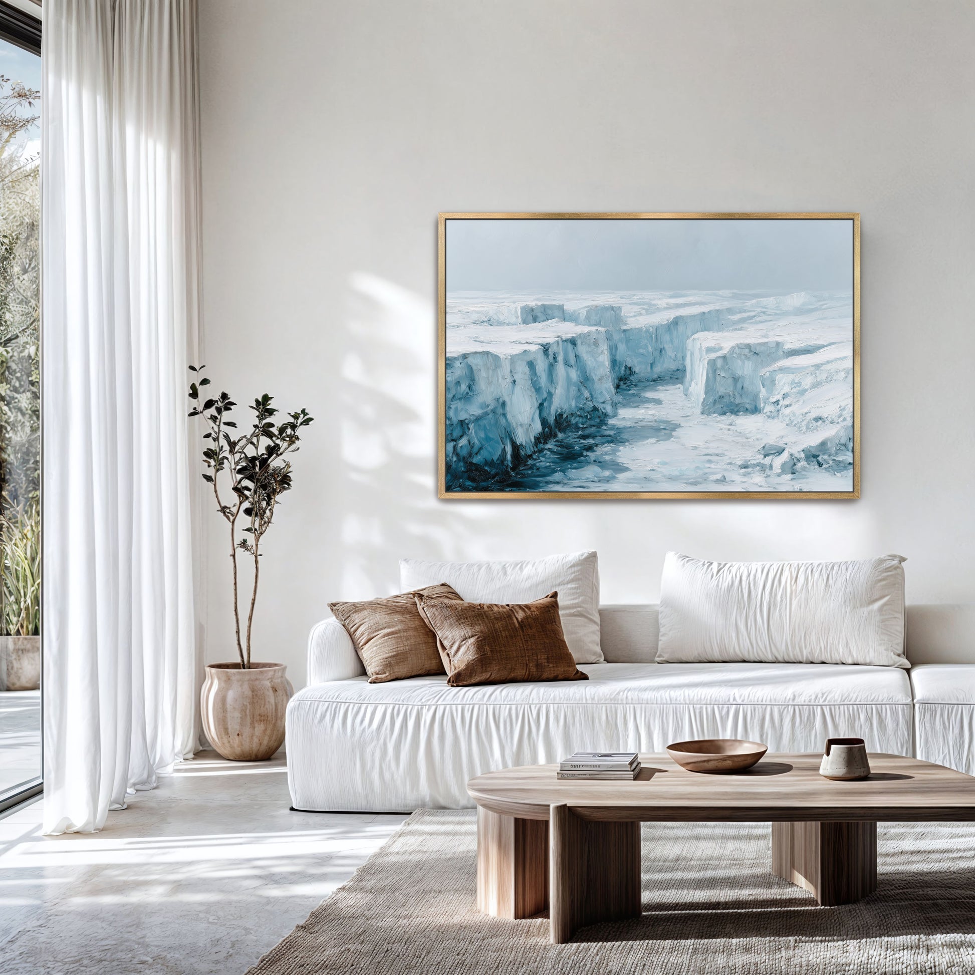 a modern living room with a large white sofa, a wooden coffee table, and a framed landscape painting of a snowy mountain scene hanging on the wall.