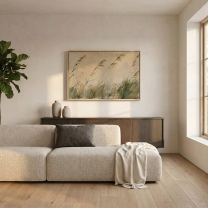 a serene living room with a large window, a beige sofa, a wooden cabinet, and a framed painting of tall grasses hanging on the wall.