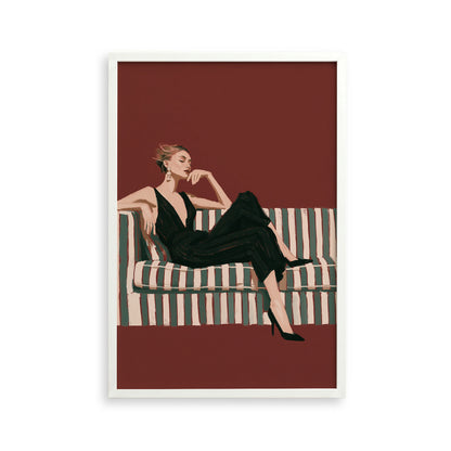A woman in a black jumpsuit is sitting on a striped couch, with her legs crossed and her head resting on her hand.