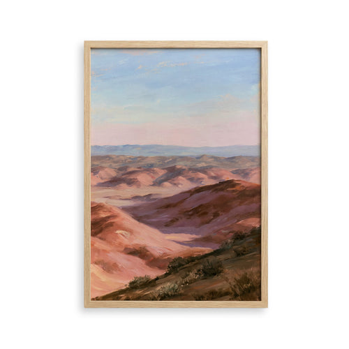 The image is a framed painting depicting a scenic landscape with rolling hills and a clear blue sky.