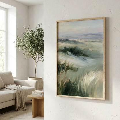a living room with a large painting of a grassy field hanging on the wall. The painting is framed in a wooden frame and appears to be a landscape artwork. In the background, there is a window that allows natural light to enter the room, and a potted plant is visible on the left side of the image.