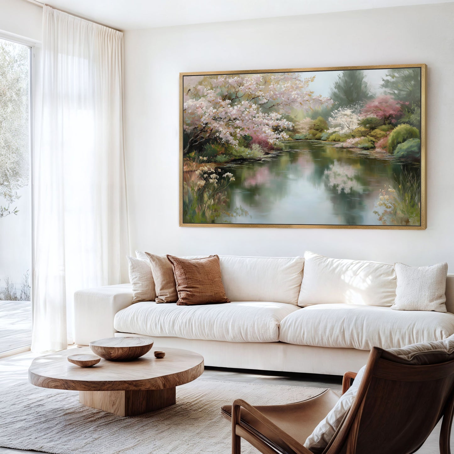 a serene living room with a large painting of a tranquil pond and lush trees hanging on the wall. The room is furnished with a white sofa, a wooden coffee table, and a brown armchair, creating a cozy and inviting atmosphere.