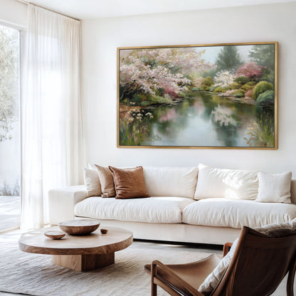 a serene living room with a large painting of a tranquil pond and lush trees hanging on the wall. The room is furnished with a white sofa, a wooden coffee table, and a brown armchair, creating a cozy and inviting atmosphere.