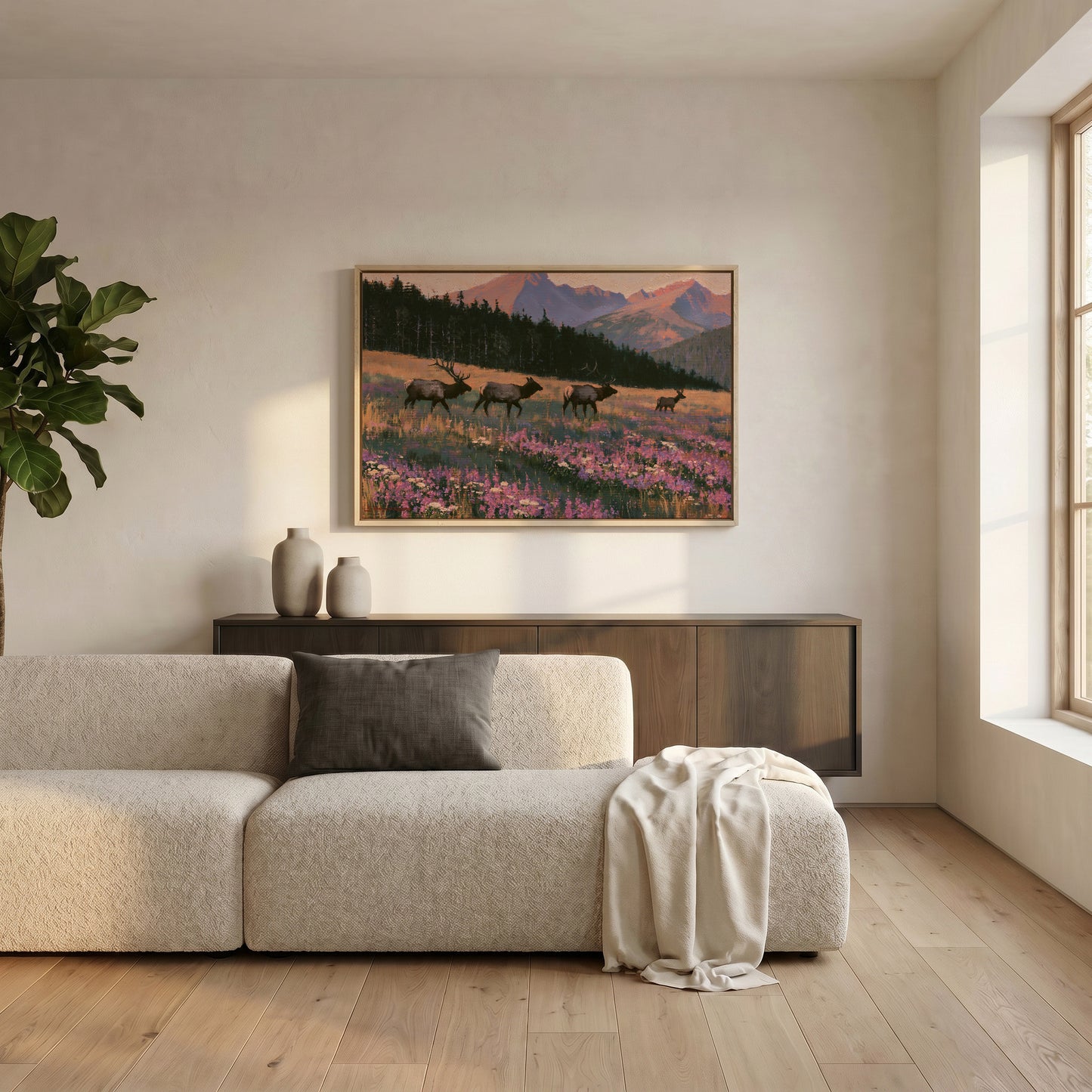 a serene living room with a large window, a beige sofa, a wooden cabinet, and a framed painting of a field with deer in the background.