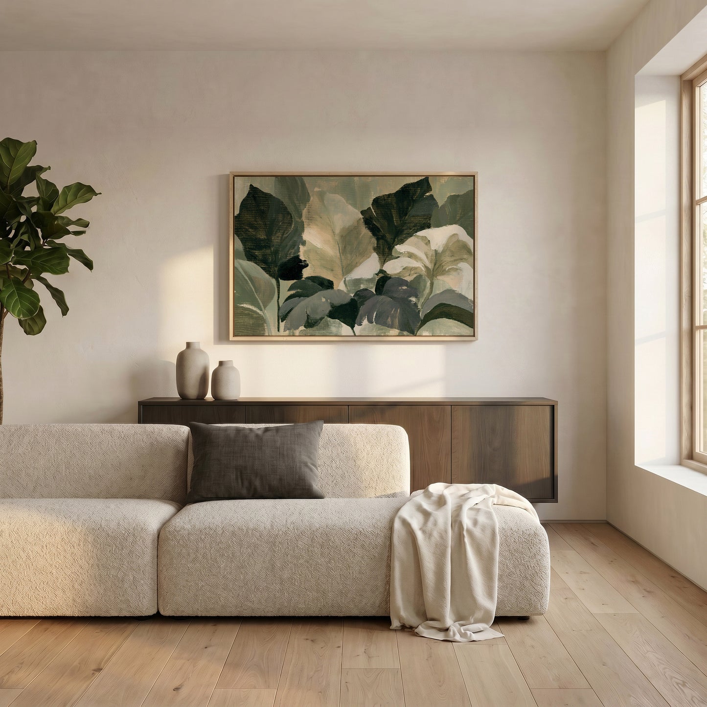 a modern living room with a large, comfortable-looking sofa, a wooden coffee table, and a large window that allows natural light to fill the space. Above the sofa, there is a framed painting of green leaves, adding a touch of nature to the room. The overall design and arrangement of the furniture and decor create a cozy and inviting atmosphere.