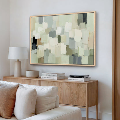 a living room with a large abstract painting hanging on the wall above a wooden console table. The console table has a lamp, a stack of books, and a bowl on it. The room has a white sofa and a wooden floor, creating a cozy and inviting atmosphere.
