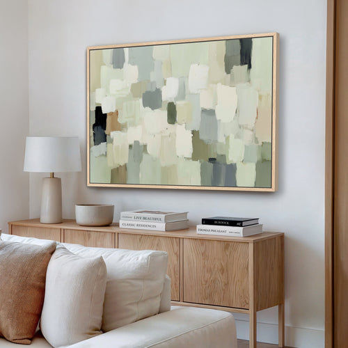 a living room with a large abstract painting hanging on the wall above a wooden console table. The console table has a lamp, a stack of books, and a bowl on it. The room has a white sofa and a wooden floor, creating a cozy and inviting atmosphere.