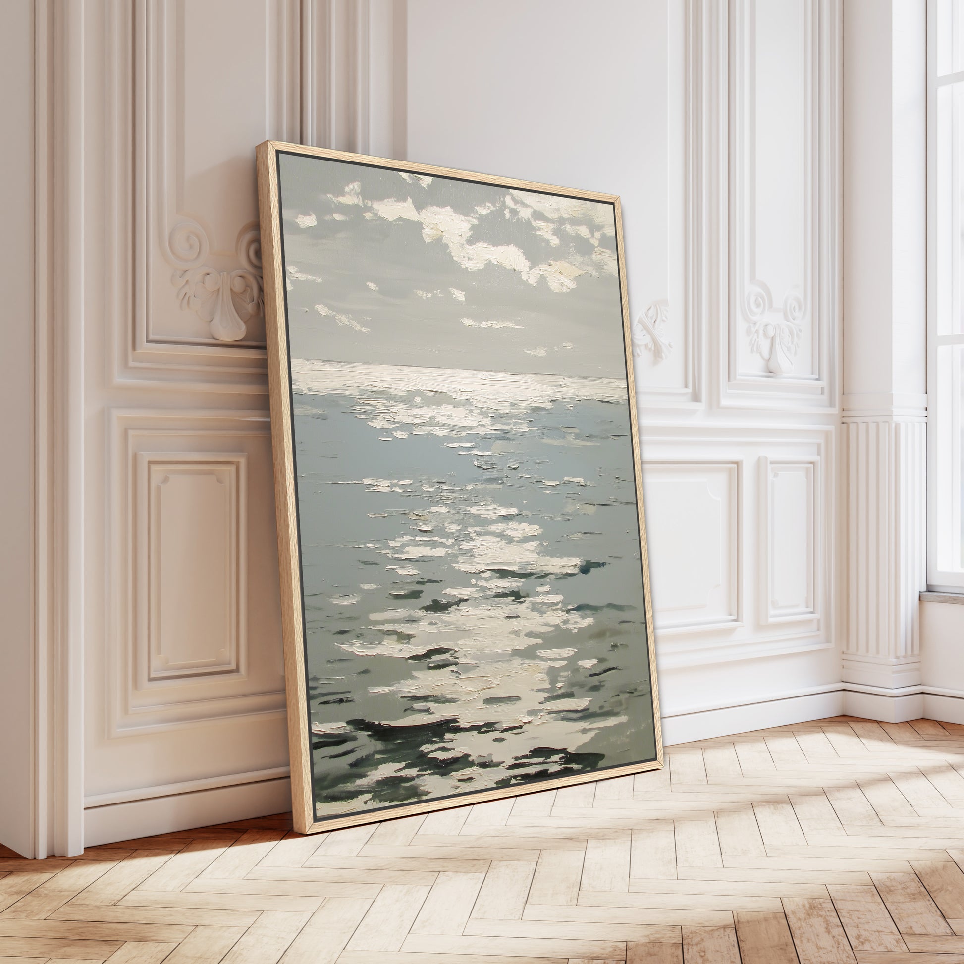 a large framed painting of a seascape, leaning against a white wall in a room with a wooden floor.
