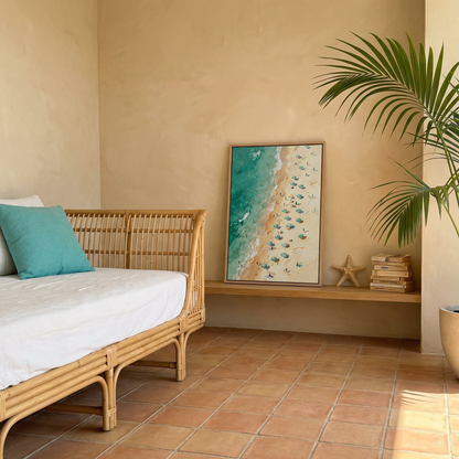 a cozy bedroom with a wicker bed, a framed beach scene, and a potted plant.
