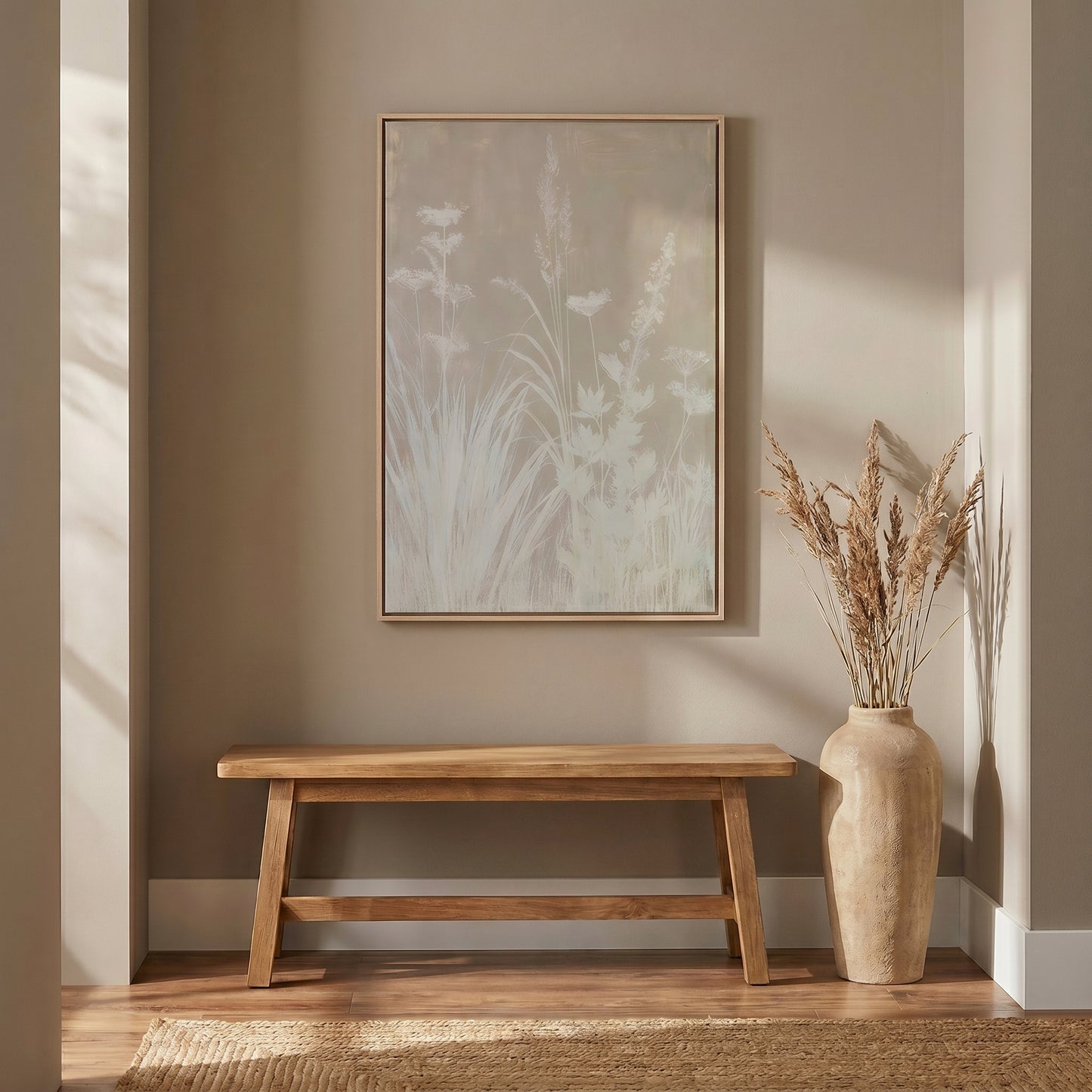 a wooden bench with a vase of dried flowers on a wooden stand, set against a beige wall with a framed picture of a plant on the wall.