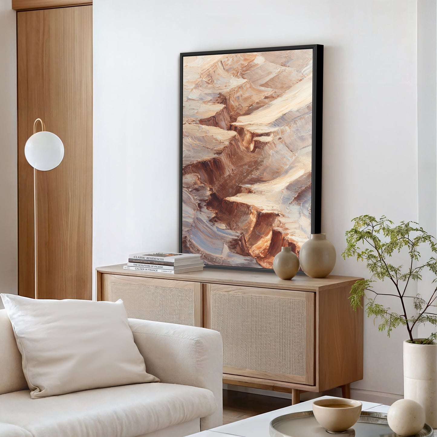a modern living room with a large abstract painting hanging on the wall above a wooden cabinet. The room has a white sofa, a floor lamp, and a plant on a table.