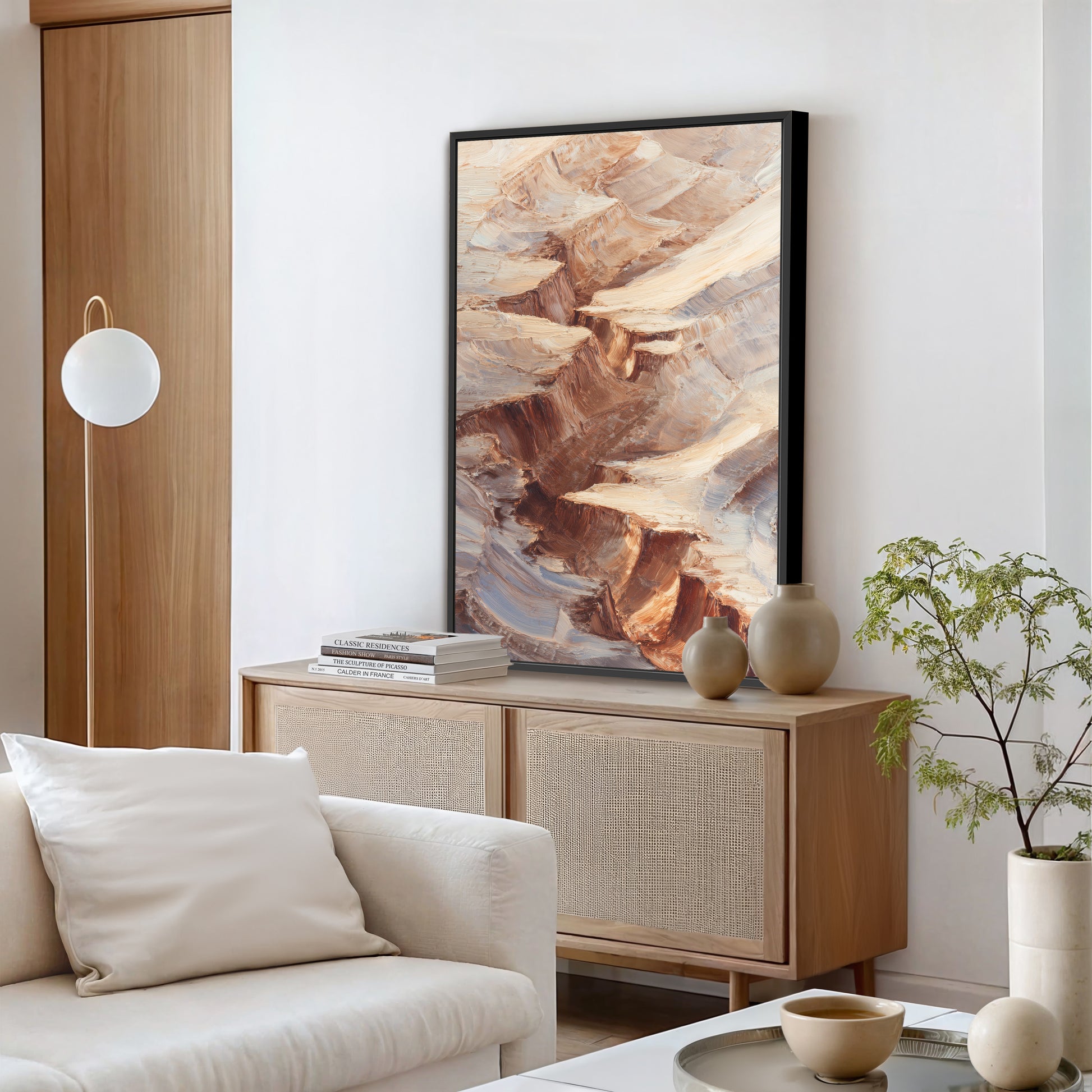 a modern living room with a large abstract painting hanging on the wall above a wooden cabinet. The room has a white sofa, a floor lamp, and a plant on a table.