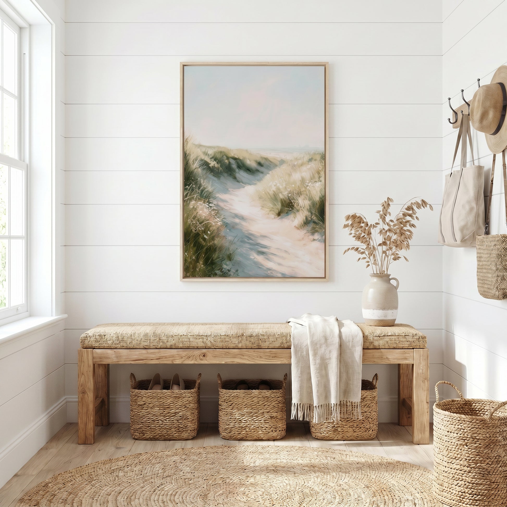 a serene and cozy entryway with a wooden bench, a large framed painting of a beach scene, and a woven basket. The room has white walls and a large window that allows natural light to fill the space.