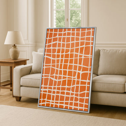 a large orange and white patterned canvas or painting displayed in a living room setting, with a beige sofa and a wooden side table visible in the background.