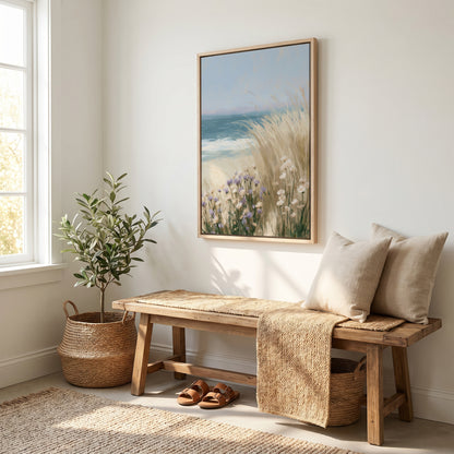 a serene and cozy living space with a wooden bench, a woven basket, and a potted plant. Above the bench, there is a framed painting depicting a beach scene with tall grasses and flowers. The room has white walls and a large window that allows natural light to fill the space, creating a warm and inviting atmosphere.