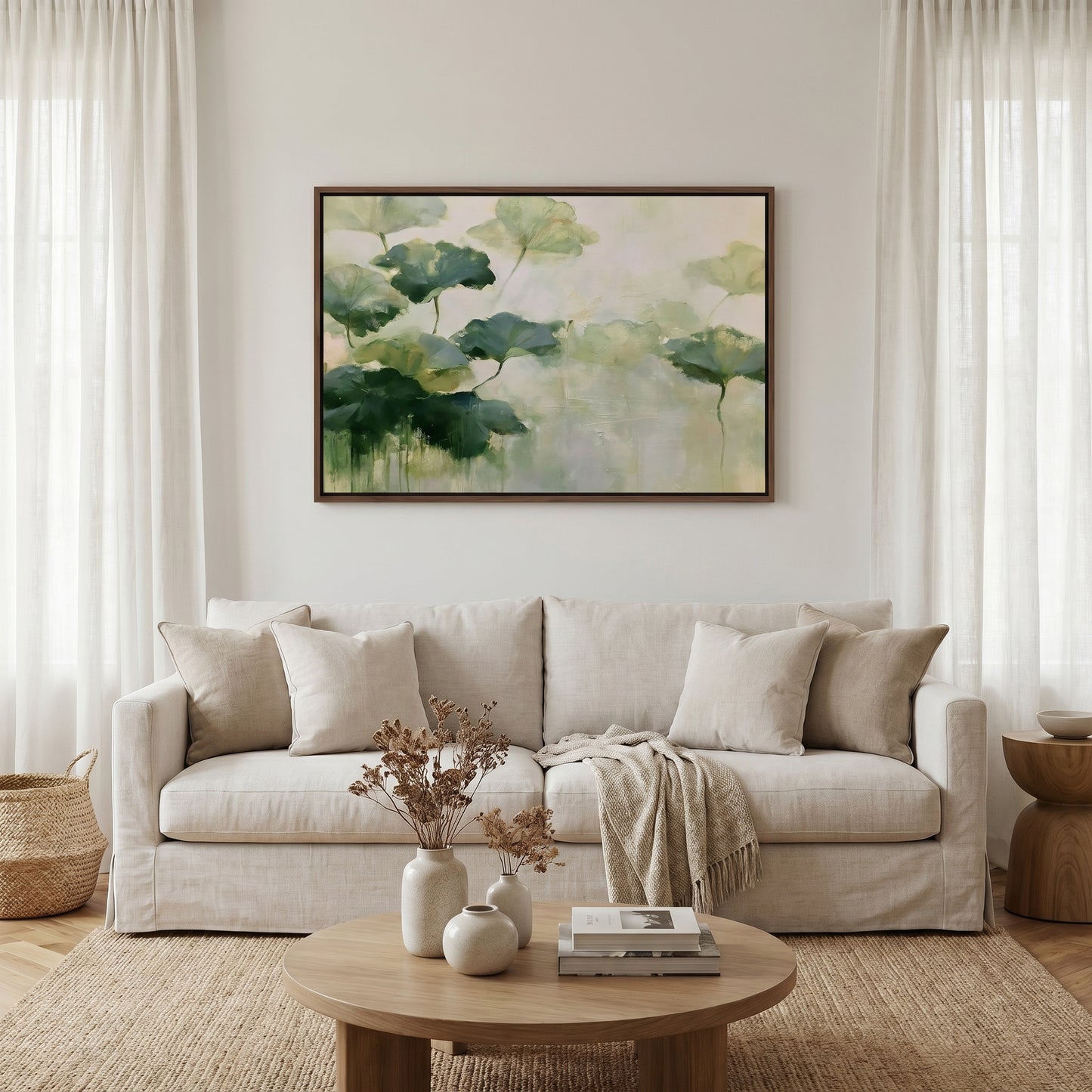 a living room with a beige sofa, a wooden coffee table, and a framed painting of green leaves hanging on the wall above the sofa.