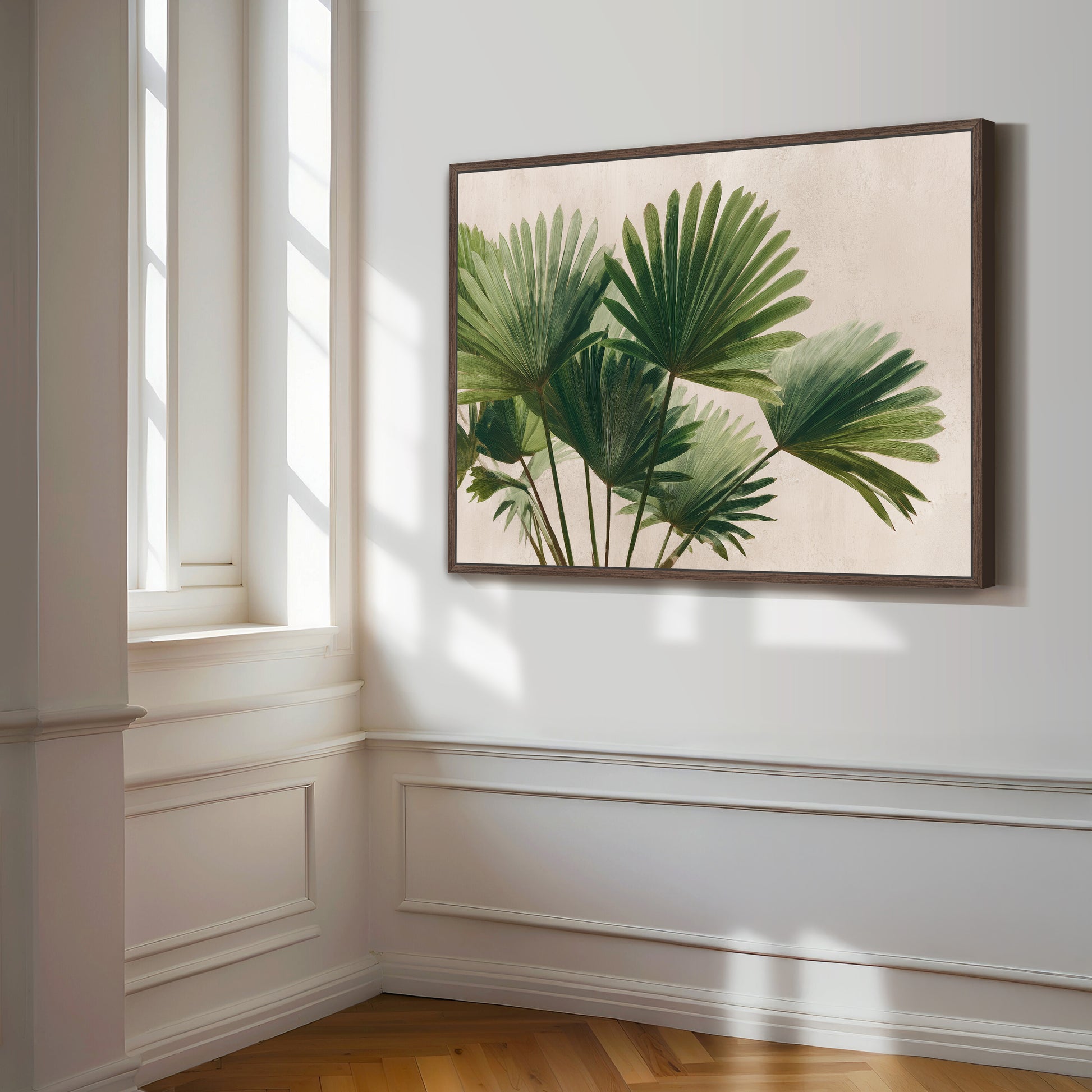 a framed painting of green palm leaves hanging on a white wall in a room with a wooden floor.