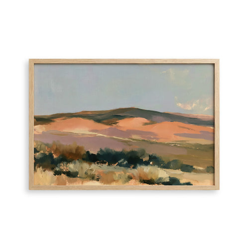 The image is a framed landscape painting depicting a desert scene with mountains in the background.