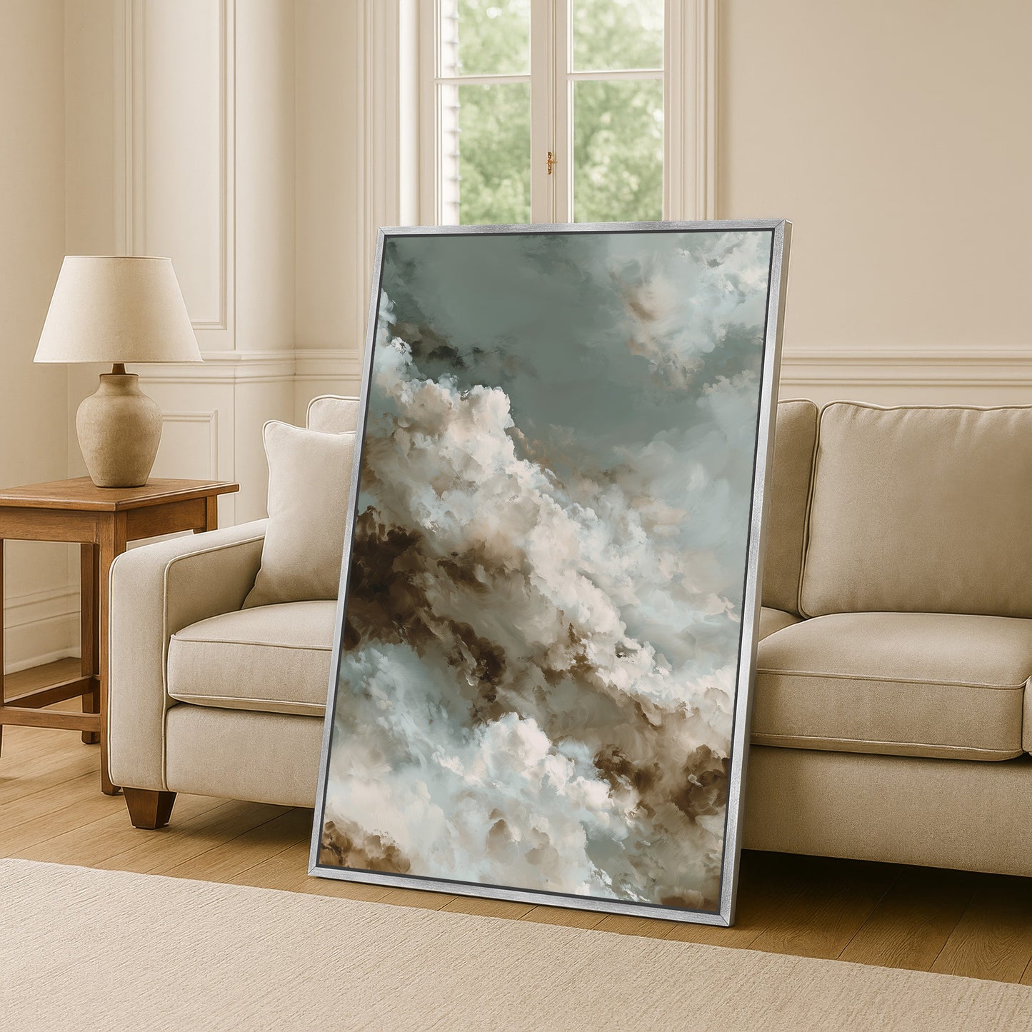 a large framed painting of clouds on a wall, with a beige sofa and a wooden side table in the background.