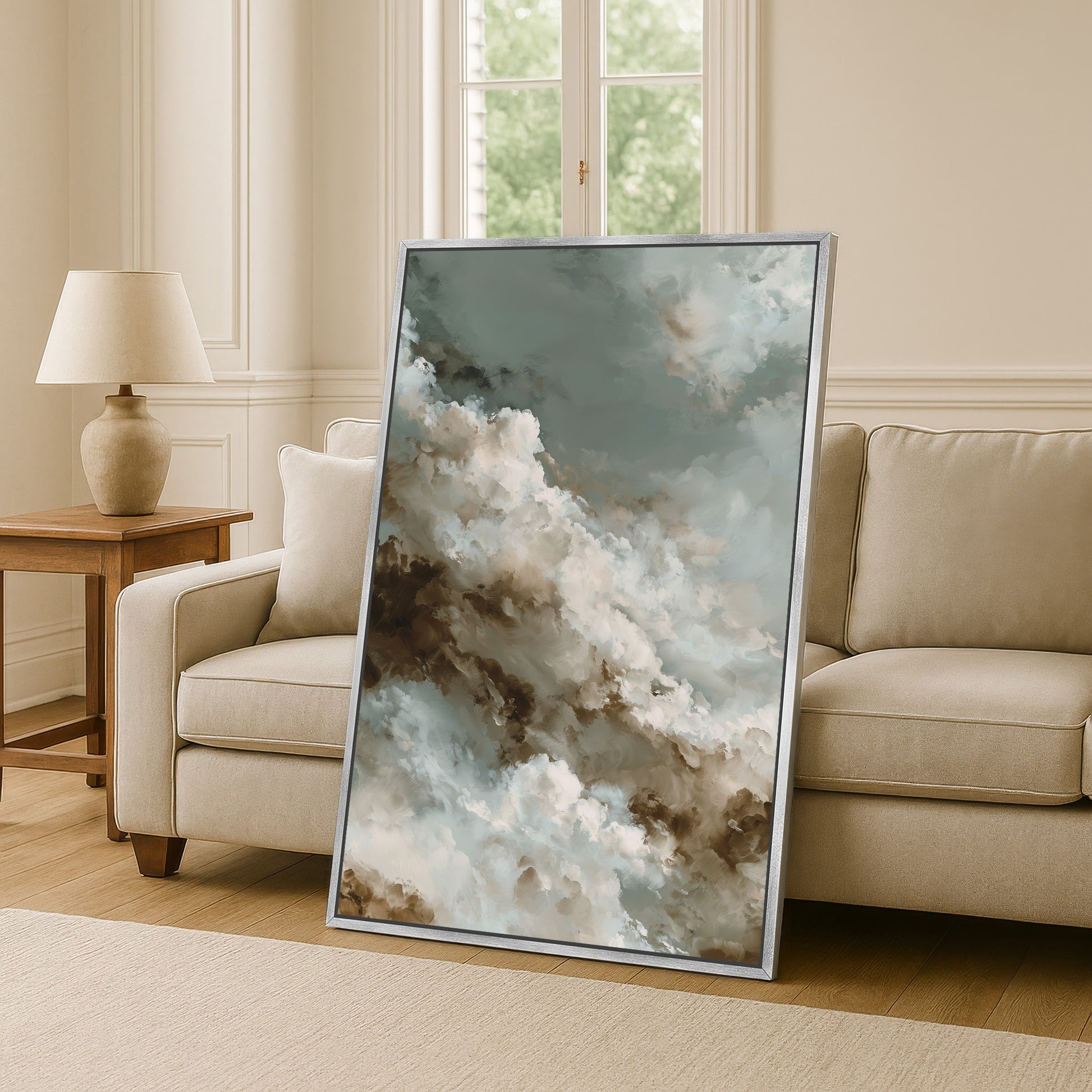 a large framed painting of clouds on a wall, with a beige sofa and a wooden side table in the background.