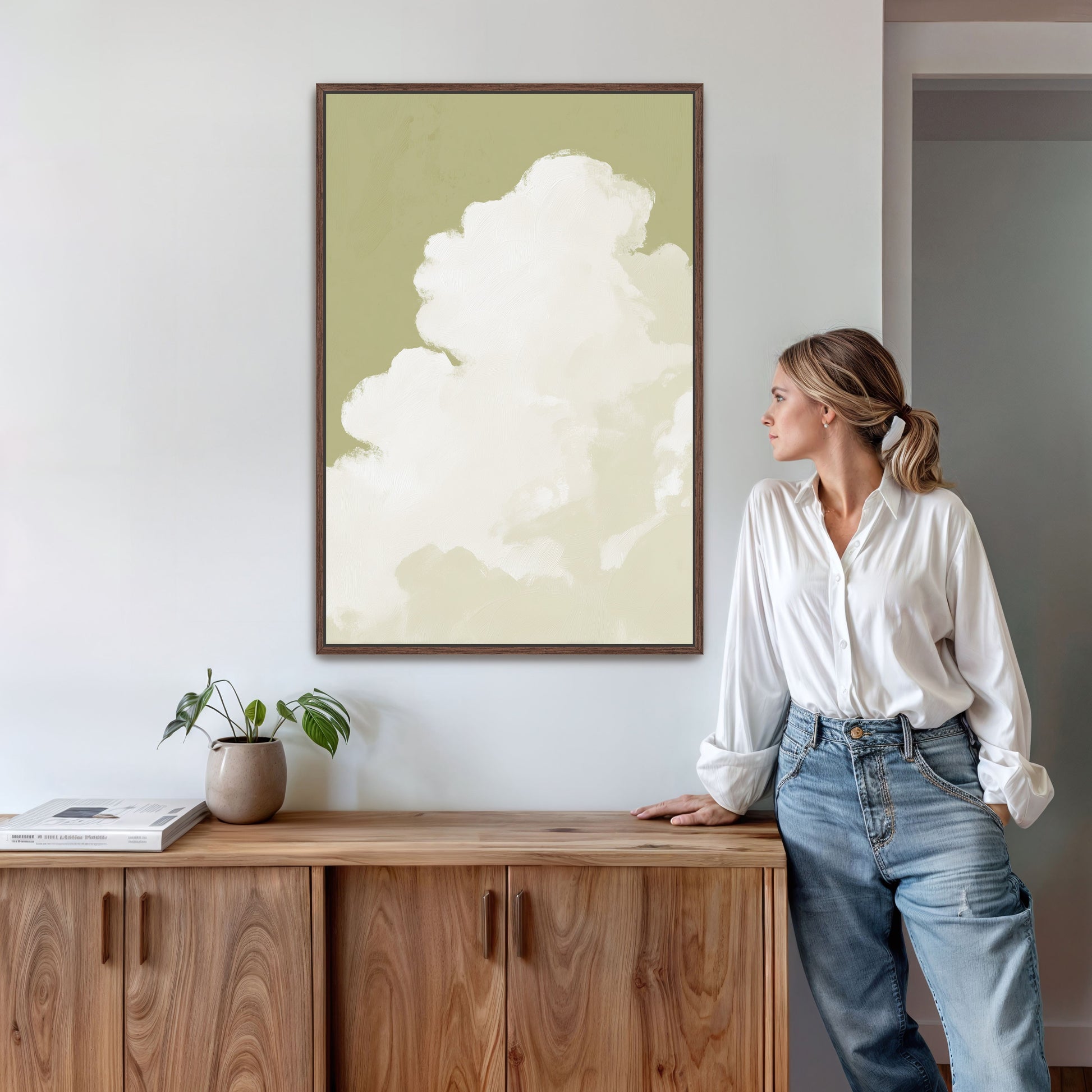 Rise Canvas Wall Art showing a single white cloud ascending against muted sage background in a wooden frame displayed on a wall above a wooden sideboard