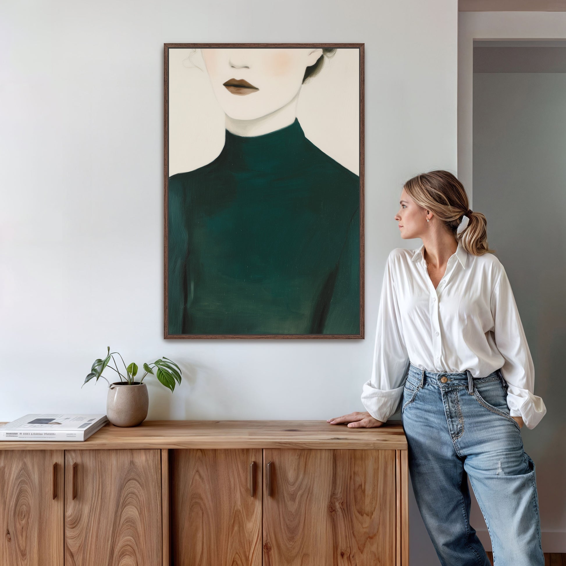 Poise Canvas Print showing faceless figure in deep emerald turtleneck, framed on wall above wooden sideboard with woman standing nearby