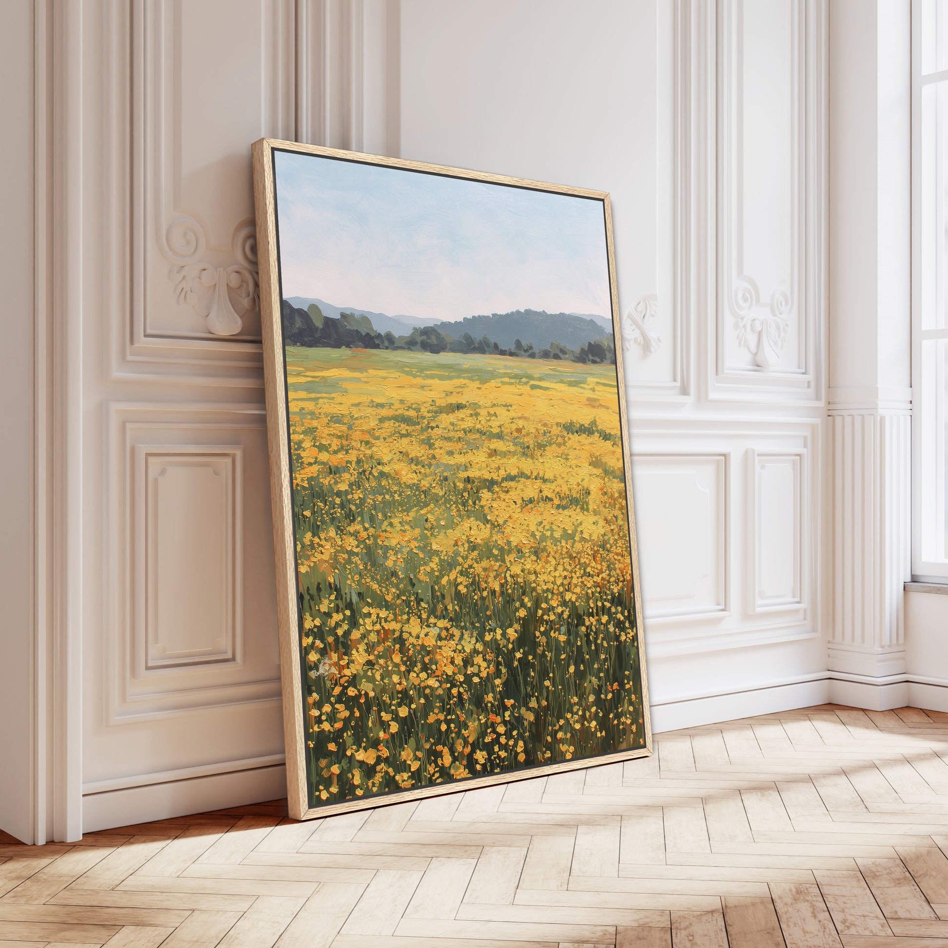 A large framed painting depicting a field of yellow flowers is leaning against a white wall in a room with a wooden floor.