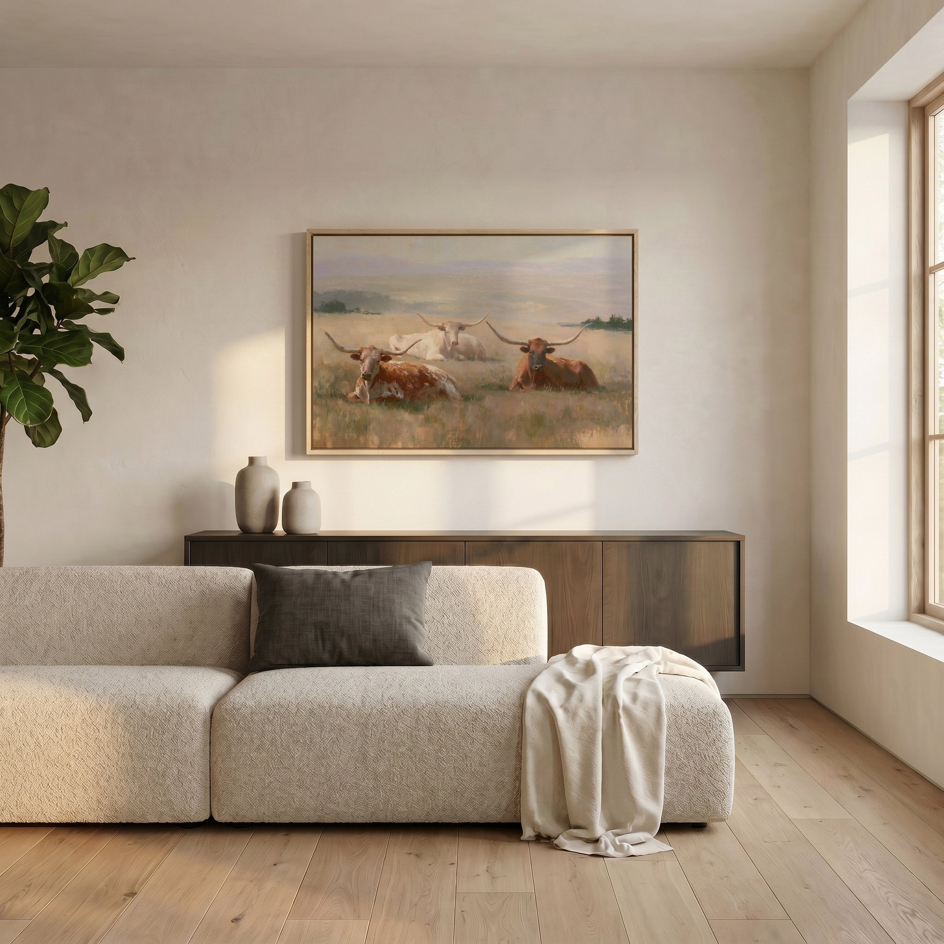 a cozy living room with a large window, a beige sofa, a wooden cabinet, and a framed painting of cows in a field hanging on the wall.